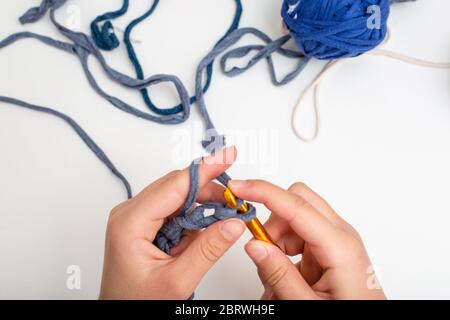 Different colored balls of yarn. Children's hands are crocheted and thread view frome above Stock Photo