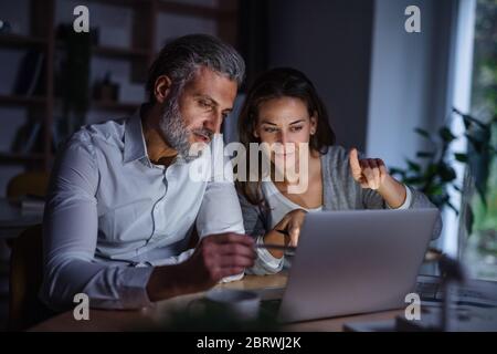 Architects with laptop sitting at the desk indoors in office, working late. Stock Photo