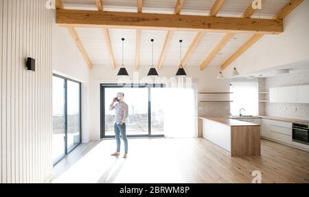 Mature man standing in new house, using smartphone. Stock Photo