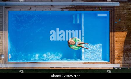 Aerial view of man lying in water in swimming pool outdoors. Stock Photo