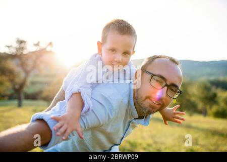 Father with small toddler son on walk on meadow outdoors, having fun. Stock Photo