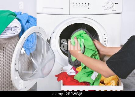Male loading dirty clothes from basket to washing machine for washed. Home appliance Stock Photo