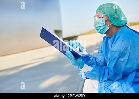 Containment Scout in front of clinic studies list for contact tracking in coronavirus or Covid-19 pandemic Stock Photo