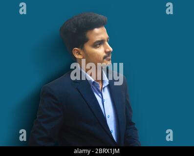 Portrait of fashionable handsome man in black suit . handsome man isolated on light blue background. Stock Photo