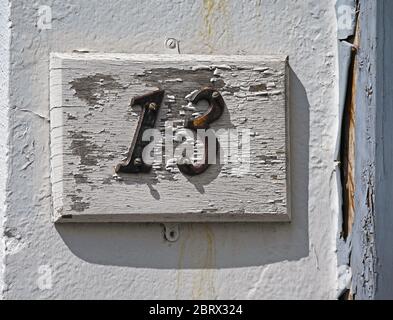 House Number 13 on wooden panel with peeling paint. Captain French Lane, Kendal, Cumbria, England, United Kingdom, Europe. Stock Photo