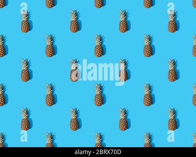 top view of whole ripe pineapples on blue colorful background, seamless pattern Stock Photo