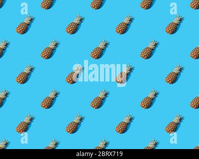 top view of whole ripe pineapples on blue colorful background, seamless pattern Stock Photo