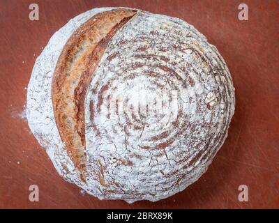 A freshly baked round sourdough loaf of bread on a bread board. from above. Stock Photo
