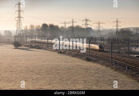Virgin Trains class 390 Pendolino train under a mass of catenary and national grid pylons on the electrified west coast mainline Stock Photo