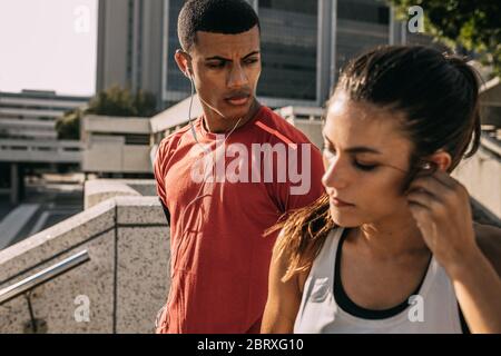 Fitness couple out in the city for morning workout routine. Man and woman in sportswear getting ready for a morning run. Stock Photo