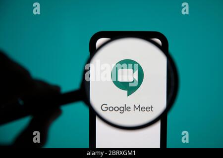 LONDON, UK - May 22 2020: Google Meet video meeting logo under magnifying glass Stock Photo