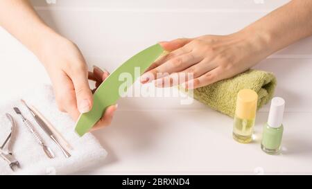 Manicure. A woman files her nails. Shorten long nails. Manicure tools. Home nail care, SPA, beauty. Long natural nails. Beauty salon. Stock Photo