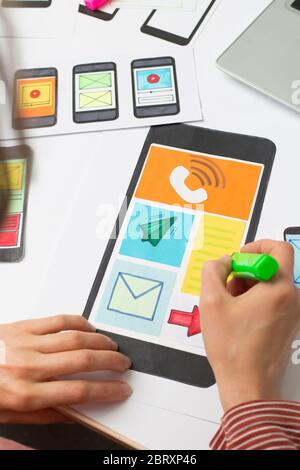 The web designer is working on an interface to mobile phone applications. The developer draws sketches of user applications for smartphones. Stock Photo