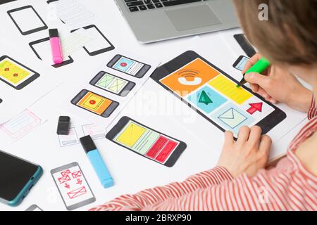 The web designer is working on an interface to mobile phone applications. The developer draws sketches of user applications for smartphones. Stock Photo