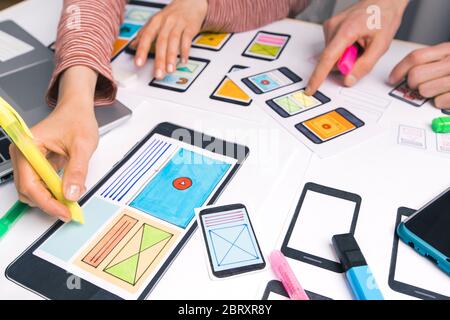 The web designer is working on an interface to mobile phone applications. The developer draws sketches of user applications for smartphones. Stock Photo