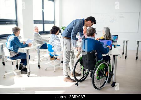 Senior man in wheelchair attending computer and technology education class. Stock Photo