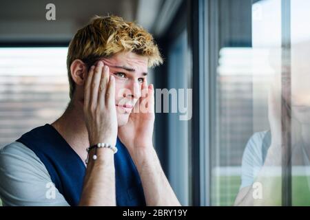 Close-up of sad and frustrated young man indoors at home. Stock Photo