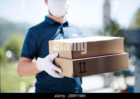 Unrecognizable courier with face mask delivering parcel, corona virus and quarantine concept. Stock Photo
