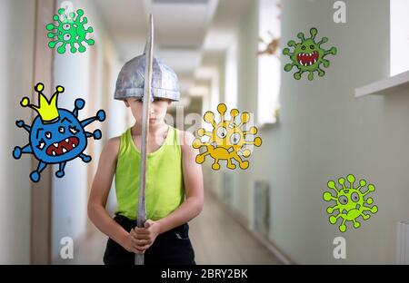A little boy stays at home with a sword to protect against the coronavirus covid-19 virus. Fight the coronavirus epidemic. A superhero capable of dest Stock Photo