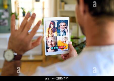 Rear view of unrecognizable man having video call on tablet at home. Stock Photo