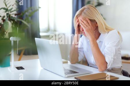 Frustrated woman engineer with laptop indoors in home office, working. Stock Photo