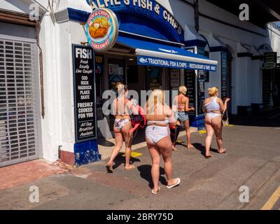 Friends wearing swimsuits walk along Southend sea front. Stock Photo