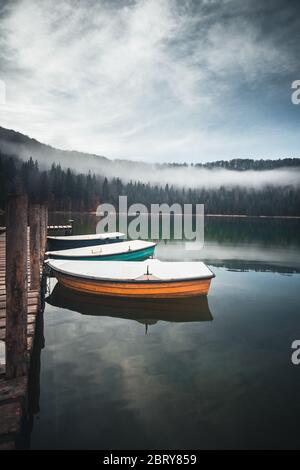 Beautiful sunrise on moody Lake Sfanta Ana with anchored boats against blue sky Stock Photo