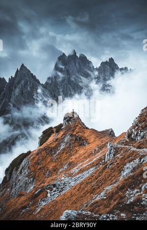 Man standing on edge of mountain feeling victorious with arms up in the air. Success, life goals, achievement concept Stock Photo