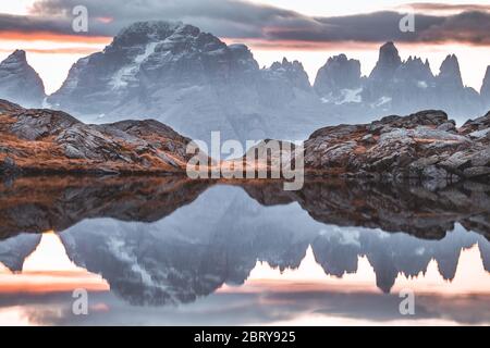 Awesome Nature Scenery. Beautiful landscape with high mountains with  illuminated peaks, stones in mountain lake, reflection, blue sky and yellow  sunlight in sunrise. Amazing nature Background. Stock Photo