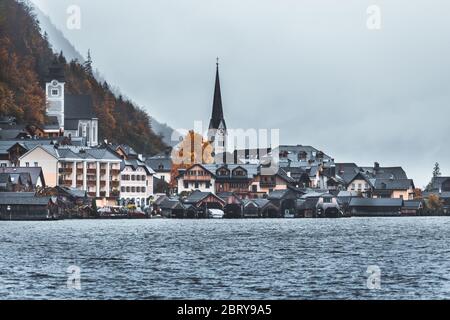 Moody fall scenery of Hallstatt at dawn, a peaceful lakeside village & a UNESCO heritage site in Salzkammergut region of Austria, with fog around and Stock Photo