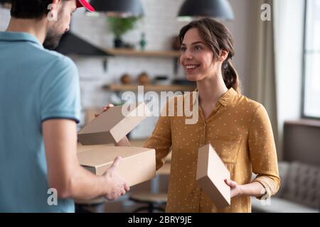 Female customer receiving boxes from a delivery person and looking satisfied Stock Photo