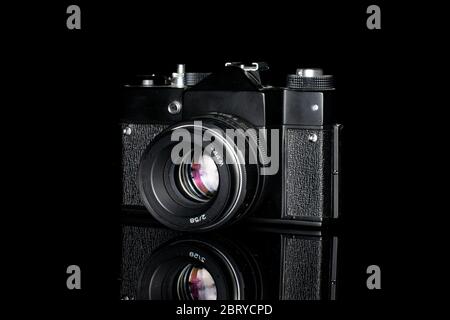 One whole black vintage camera isolated on black glass Stock Photo