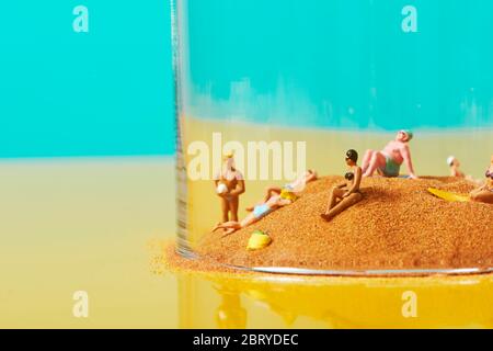 some miniature people wearing swimsuit relaxing on the sand in a bell jar, symbolizing different ideas, such as the greenhouse effect or the protectio Stock Photo