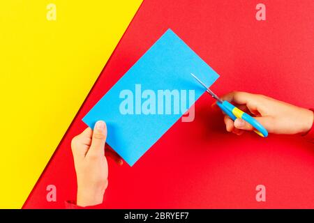 Kid,Hands,Cutting,Light,Blue,Colored,Paper,With,Scissors