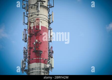 Red and white high heating plant chimney serving as antenna mast with copy space Stock Photo