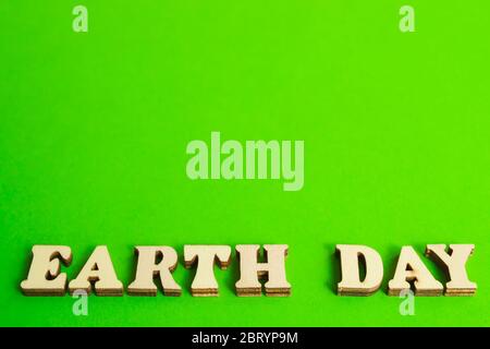 Earth Day. Words made from simple wooden letters on a green background. Environmental protection concept. Space for text Stock Photo