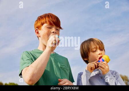 Two boys standing outdoors, eating ice cream cones. Stock Photo