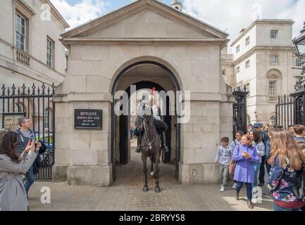 Crowds of tourists photograph the mounted guardsmen of the Blues and Royals on duty at the entrance to Horse Guards in Whitehall, London, UK Stock Photo
