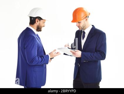 Construction, architecture, support concept. Entrepreneur and architect isolated on white background. Engineers with happy faces. Business partners look at building plan. Architects discuss project. Stock Photo