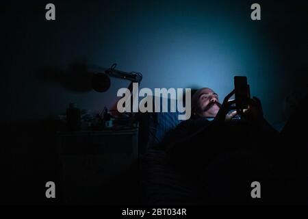 person self isolating in bed wearing a hazmat suit and mask Stock