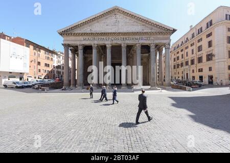 Rome, Italy - 19 May 2020: Men in business suits wearing face masks walk in group across the otherwise mostly empty Pantheon square in Rome, Italy. Stock Photo