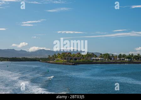 Denarau Islands Bungalows and palm trees in Fiji. A mountain chain in the background and the south sea in front of it Stock Photo