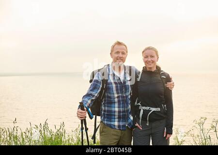 Two hikers, man and woman, embracing on a coastal path Stock Photo