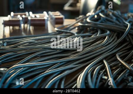 Close-up of a huge bunch of metal flexible tubes with nuts interconnected in a factory. The concept of modern electronic and IT technology. Stock Photo