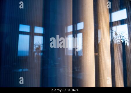 Vertical wide blinds outside the window in the light of the sunset, a reflection of office windows. Stock Photo