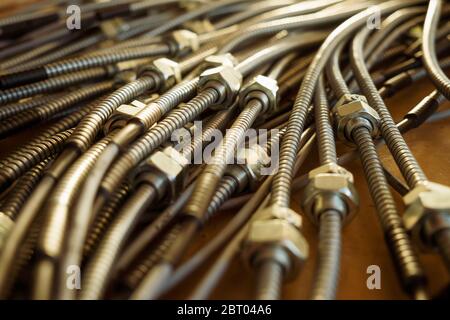 Close-up of a huge bunch of metal flexible tubes with nuts interconnected in a factory. The concept of modern electronic and IT technology. Stock Photo