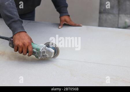 The mechanic is using a grinding machine for cut in half of cement board. Stock Photo