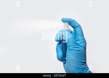 Hand in protective glove spraying alcohol or cleanser. Disinfection or hygiene concept on Coronavirus outbreak. White background. Copy space Stock Photo