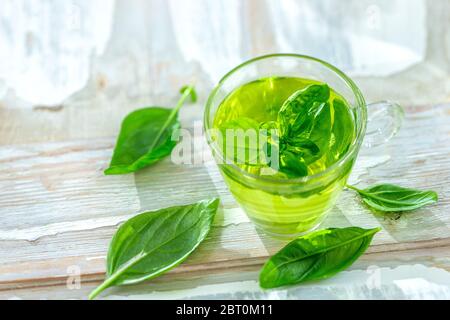 Herbal medicine : calming tea in a tea cup with basil leaves on a kitchen table Stock Photo