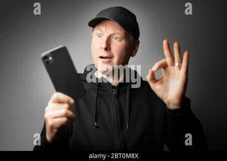 Man in black happily surprised with the message on the phone or phone itself Stock Photo